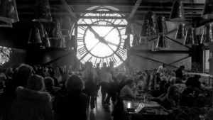 un bar affollato con un grande orologio sullo sfondo